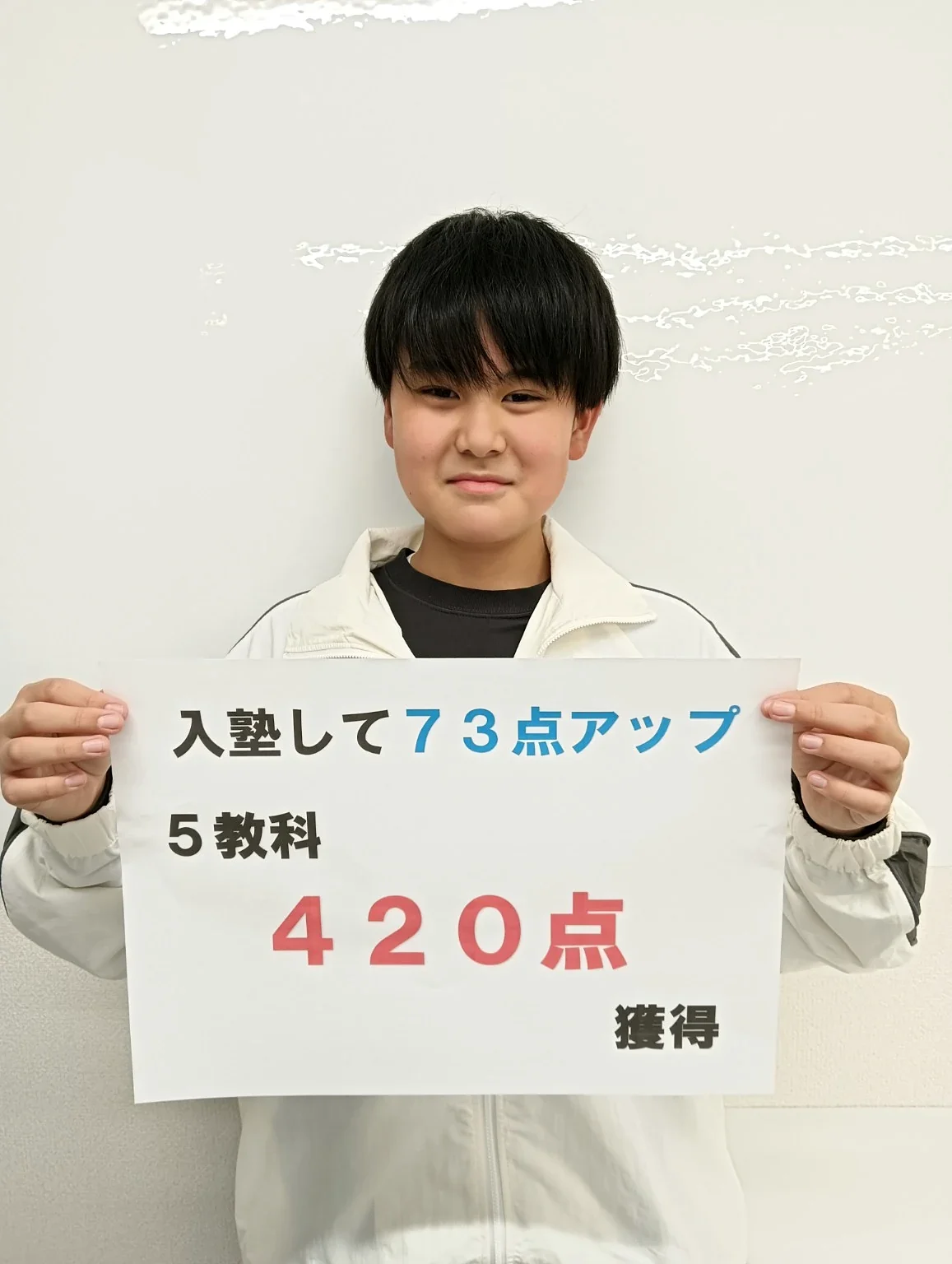 入塾後73点アップ、5教科420点獲得と書かれたボードを持つ生徒