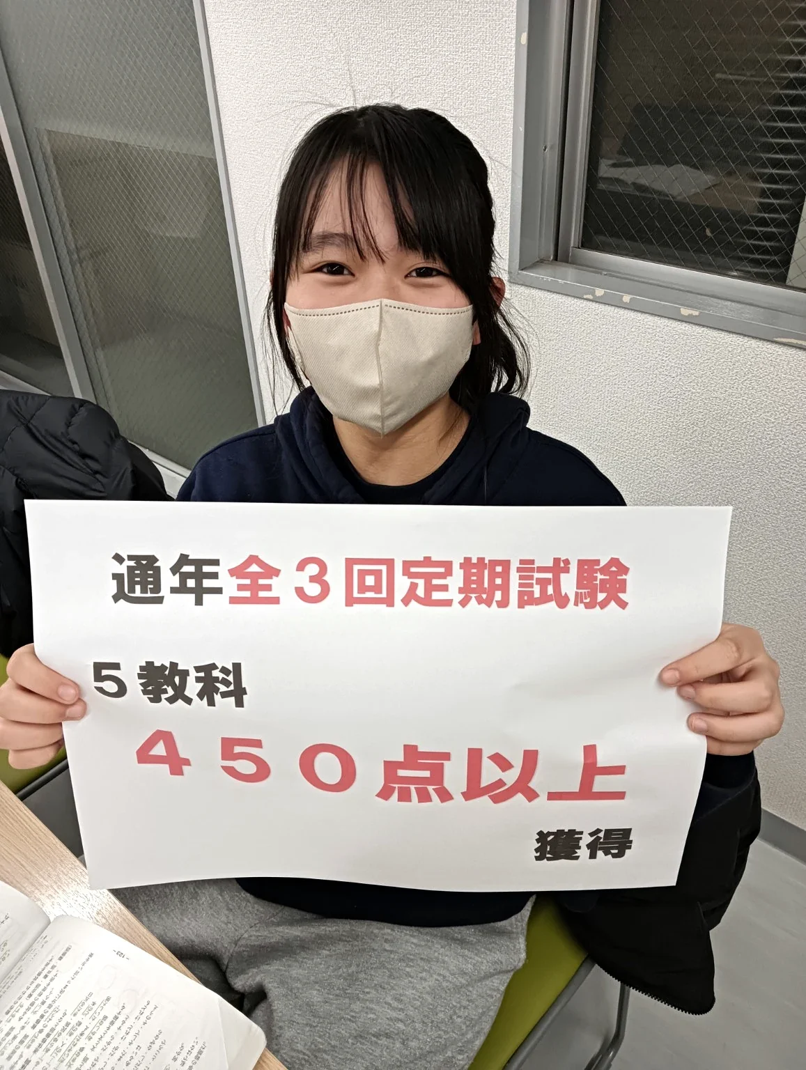 通年全3回定期試験、5教科450点以上獲得と書かれたボードを持つ生徒