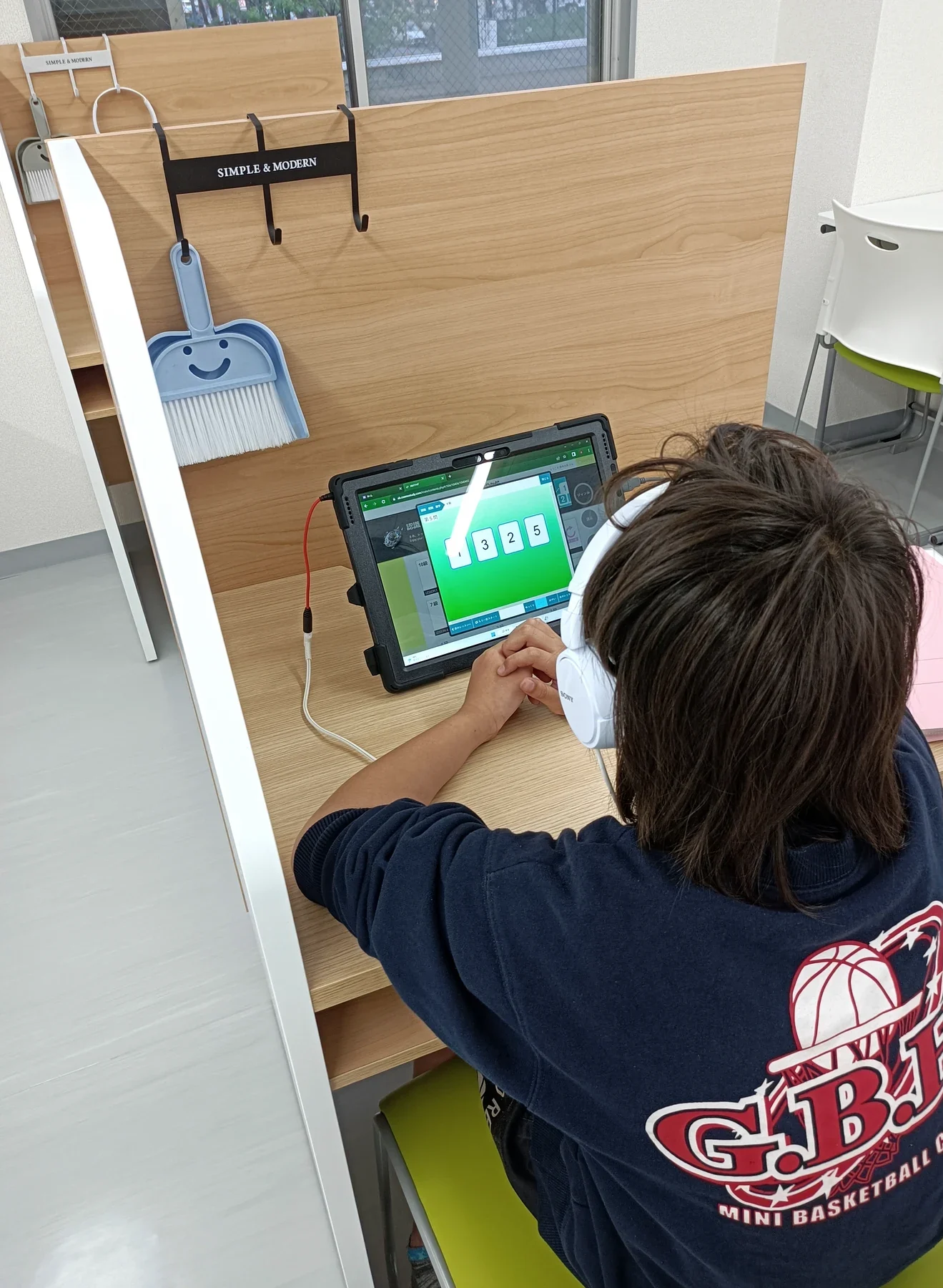 個別ブースでタブレットの問題に取り組む子ども